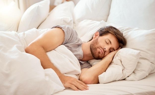 Mann schläft friedlich in einem hellen Bett mit weißer Bettwäsche