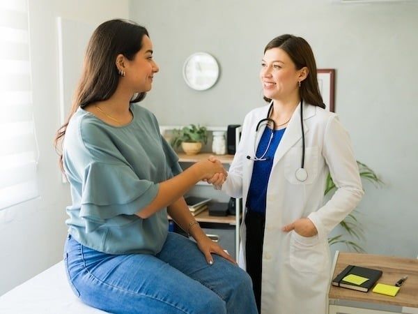 Ärztin und Patientin führen ein freundliches Gespräch im Untersuchungsraum